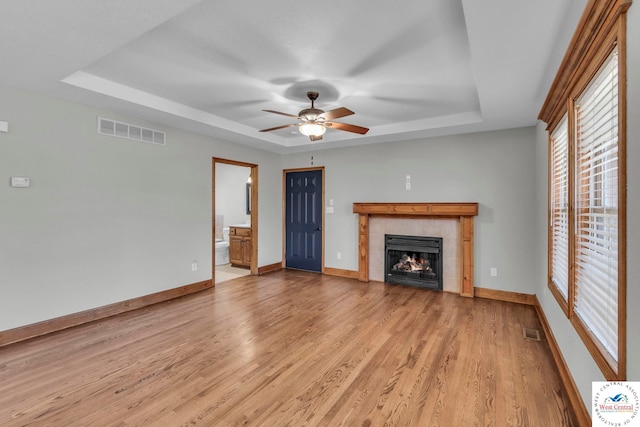 unfurnished living room with light wood-style flooring, visible vents, and a raised ceiling