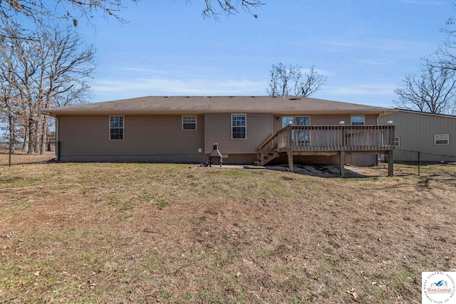 rear view of house with a lawn, fence, and a wooden deck