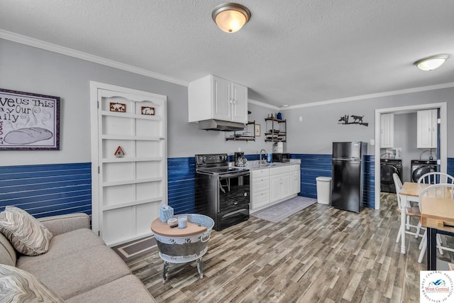 kitchen with under cabinet range hood, washer and dryer, a textured ceiling, black appliances, and a sink