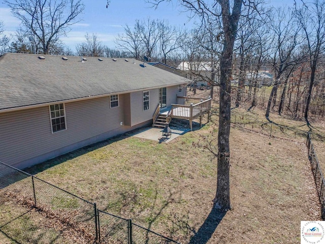 back of house with a shingled roof, a yard, fence, and a deck