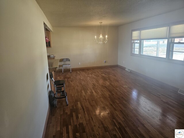 interior space featuring visible vents, a textured ceiling, dark wood-style floors, baseboards, and a chandelier