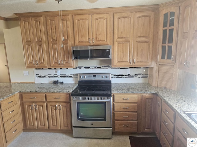 kitchen with glass insert cabinets, light stone countertops, decorative backsplash, appliances with stainless steel finishes, and brown cabinetry