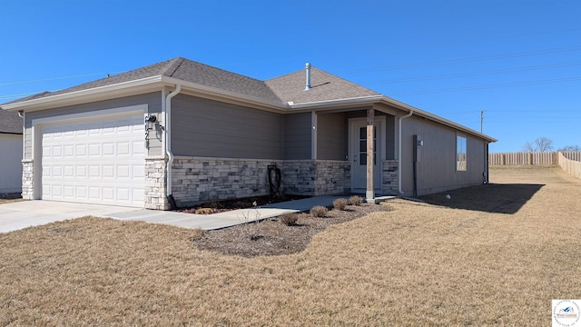 view of front of home with driveway, roof with shingles, an attached garage, fence, and a front yard