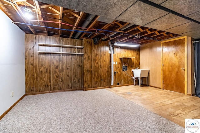 finished basement with wooden walls, carpet, baseboards, and a sink