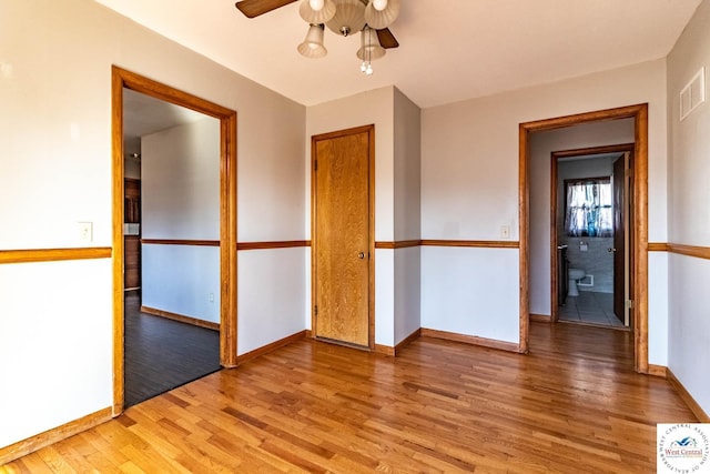 unfurnished room with light wood-type flooring, baseboards, visible vents, and a ceiling fan