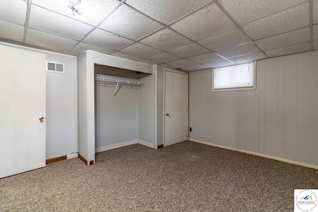 basement with carpet, visible vents, a drop ceiling, and baseboards