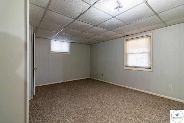 basement with a drop ceiling, baseboards, and carpet