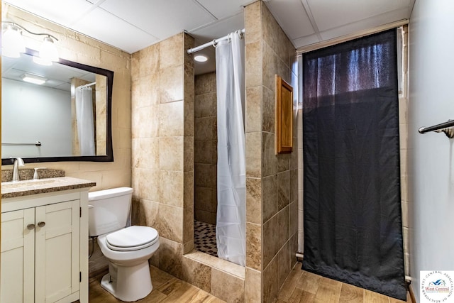 bathroom featuring a shower stall, toilet, tile walls, and wood finished floors