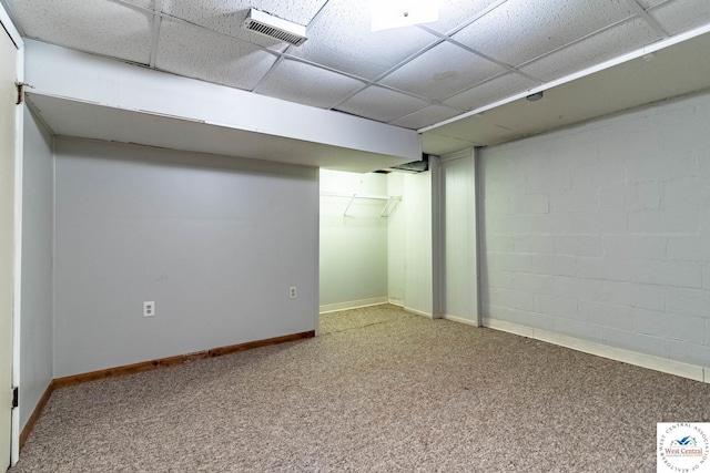 finished below grade area featuring visible vents, baseboards, a paneled ceiling, carpet floors, and concrete block wall