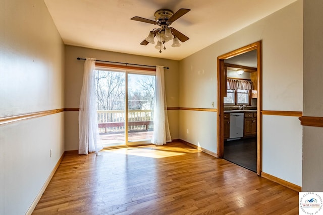 spare room with baseboards, light wood finished floors, and ceiling fan