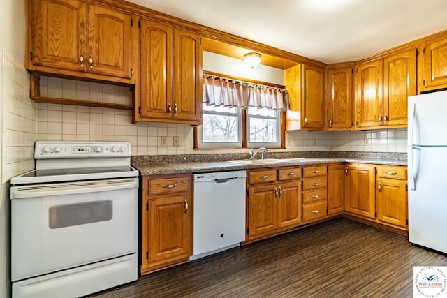 kitchen with a sink, white appliances, and brown cabinetry