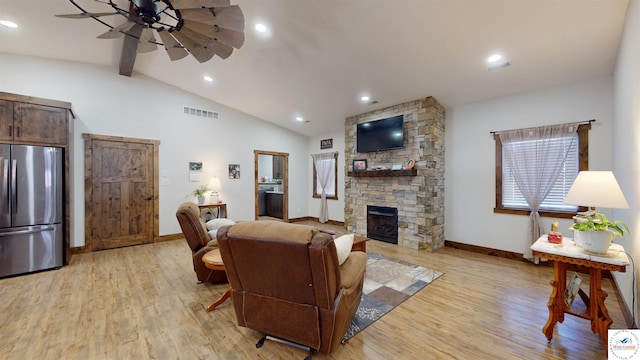 living room featuring light wood-type flooring, a fireplace, visible vents, and baseboards