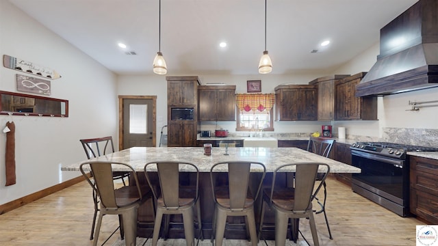 kitchen with custom range hood, stainless steel gas stove, a kitchen island, dark brown cabinetry, and black microwave