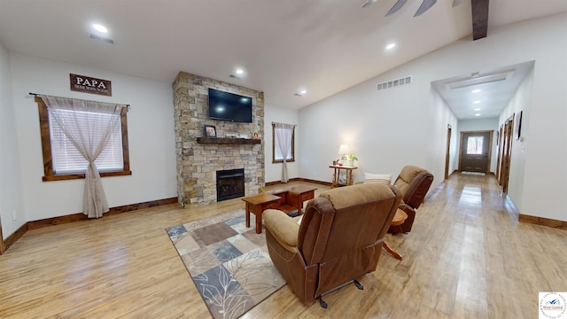 living area featuring vaulted ceiling with beams, a stone fireplace, visible vents, baseboards, and light wood finished floors