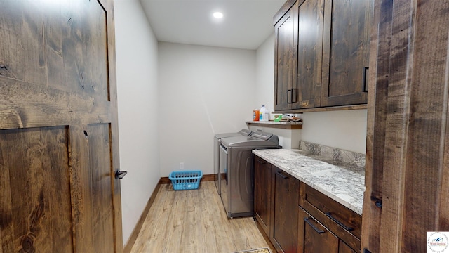 washroom with baseboards, washing machine and clothes dryer, cabinet space, and light wood-style floors