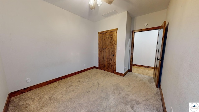 unfurnished bedroom featuring light carpet, visible vents, a ceiling fan, and baseboards