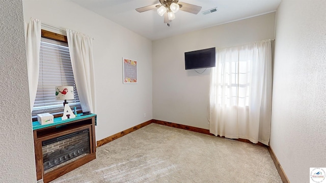 interior space featuring light carpet, a ceiling fan, visible vents, and baseboards