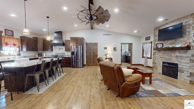 living area featuring baseboards, vaulted ceiling with beams, a stone fireplace, light wood-style floors, and recessed lighting