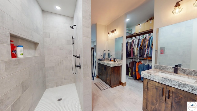 full bathroom featuring wood finished floors, walk in shower, two vanities, and a sink