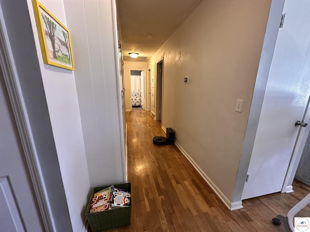 corridor with baseboards and wood finished floors