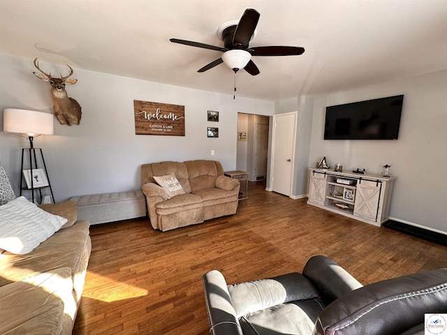 living area featuring ceiling fan, baseboards, and dark wood-style flooring