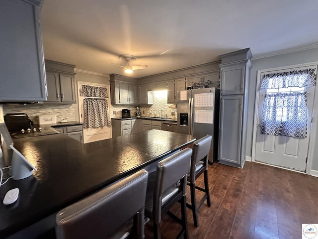 kitchen featuring stainless steel appliances, dark countertops, gray cabinets, and crown molding