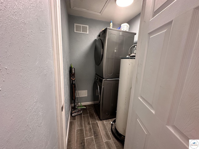 washroom with laundry area, visible vents, stacked washer / dryer, a textured wall, and wood tiled floor