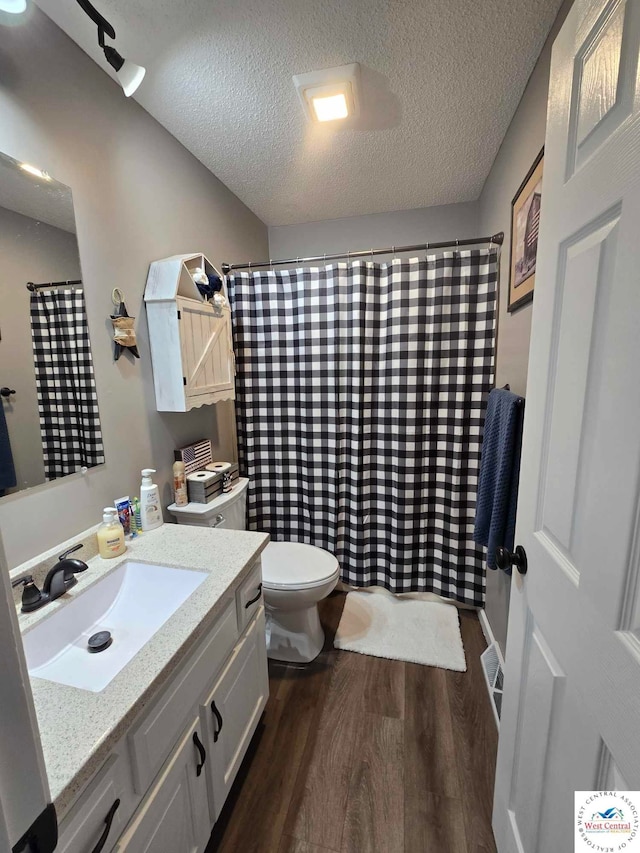 bathroom with toilet, vanity, a textured ceiling, and wood finished floors