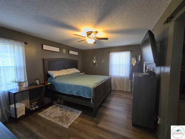 bedroom with ceiling fan, a textured ceiling, and dark wood-style flooring