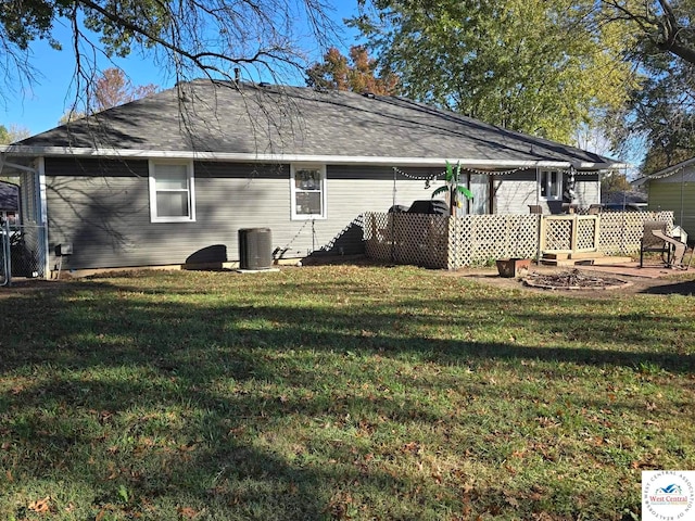 back of house featuring central AC unit, fence, and a yard