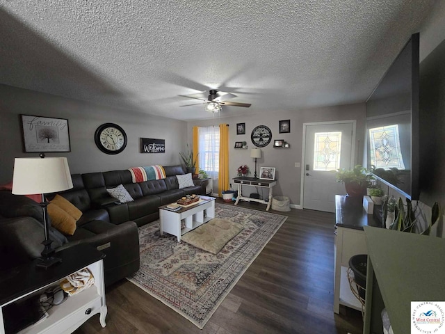 living room featuring ceiling fan, a textured ceiling, baseboards, and dark wood-style flooring