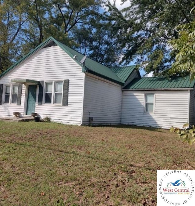 view of side of property featuring metal roof and a lawn