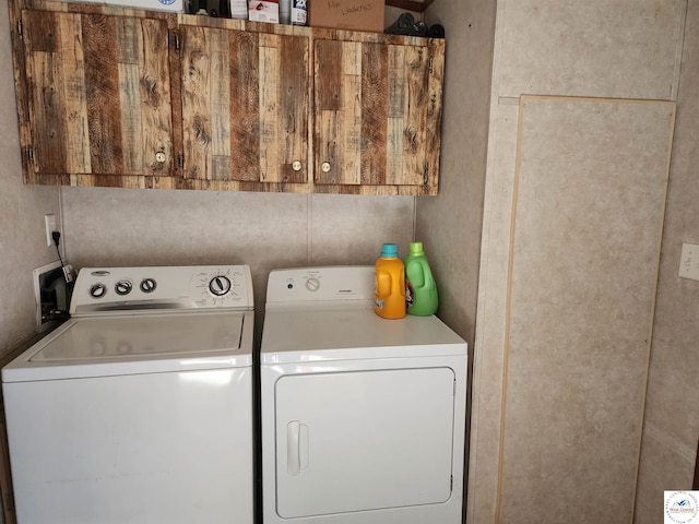 clothes washing area featuring washing machine and dryer and cabinet space