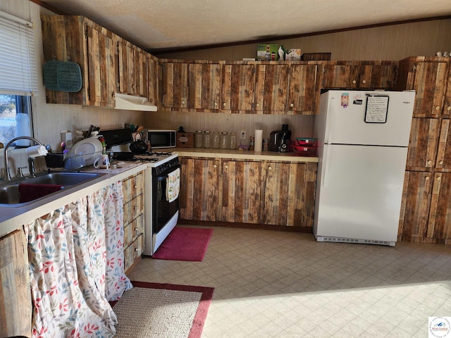 kitchen featuring light countertops, freestanding refrigerator, a sink, gas range, and under cabinet range hood