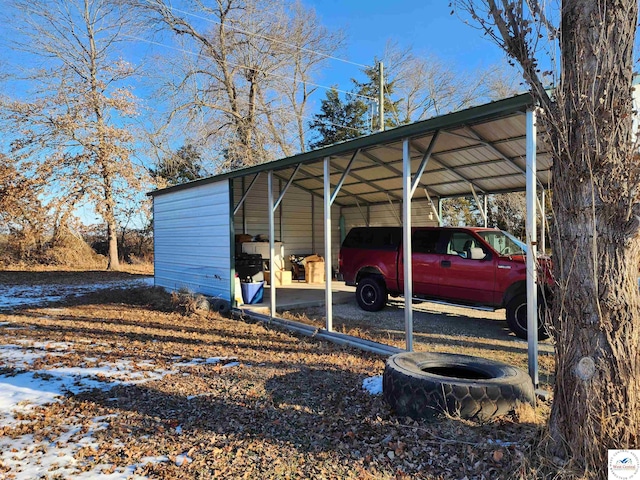 snow covered parking featuring a detached carport