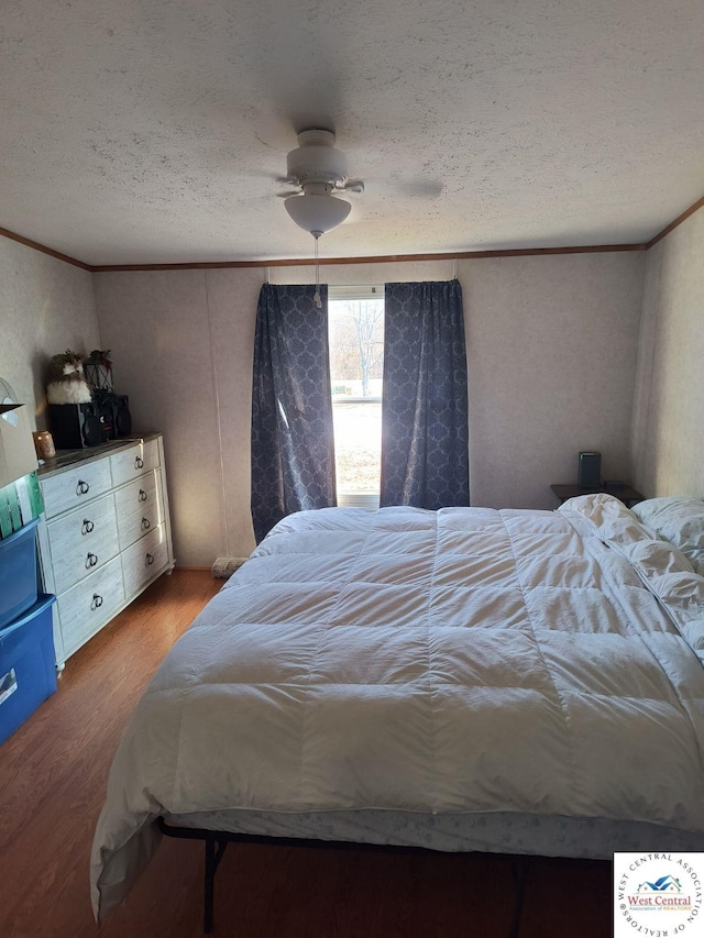 bedroom featuring a textured ceiling, a ceiling fan, crown molding, and wood finished floors