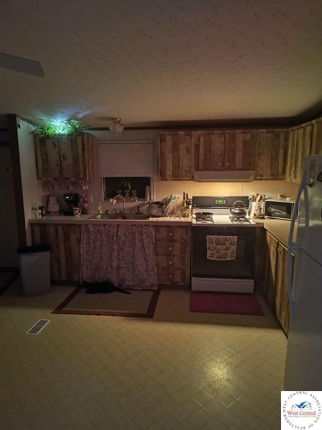 kitchen with extractor fan, visible vents, range with gas stovetop, light countertops, and freestanding refrigerator