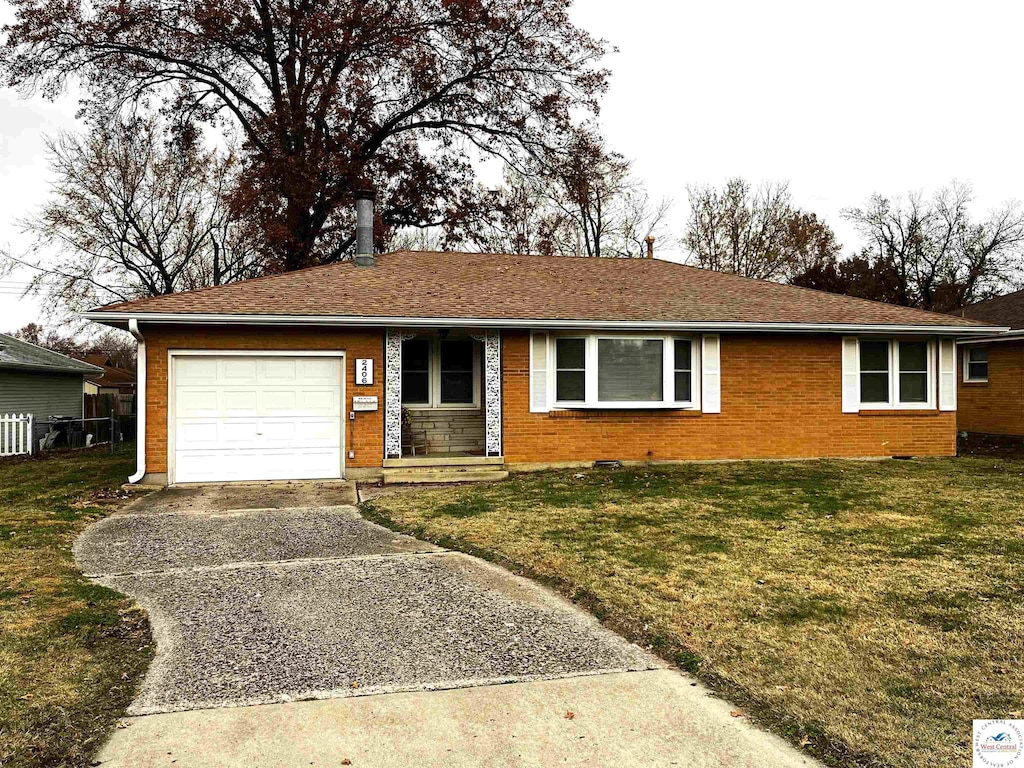 single story home with an attached garage, brick siding, driveway, and a front lawn