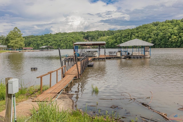 view of dock with a water view, boat lift, and a view of trees