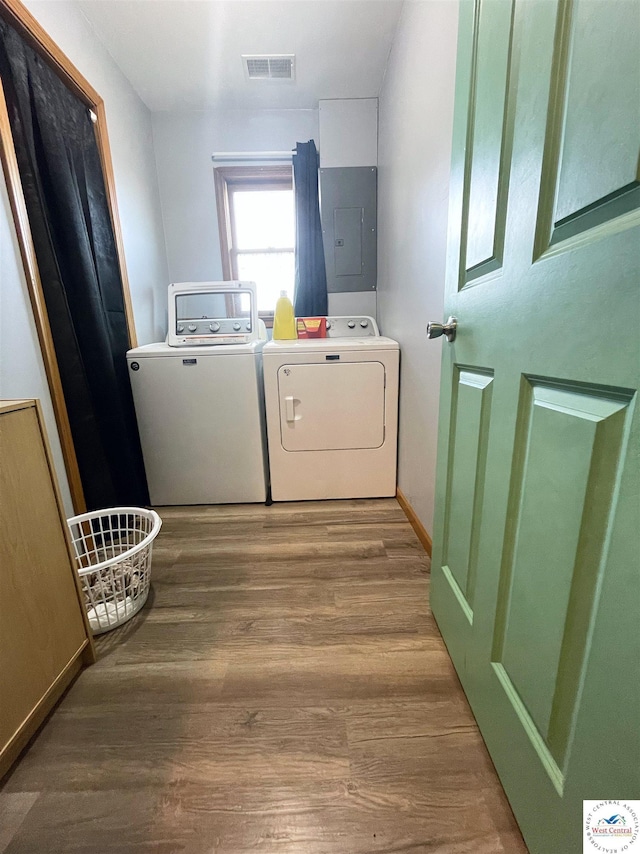 clothes washing area with laundry area, wood finished floors, visible vents, electric panel, and washer and clothes dryer