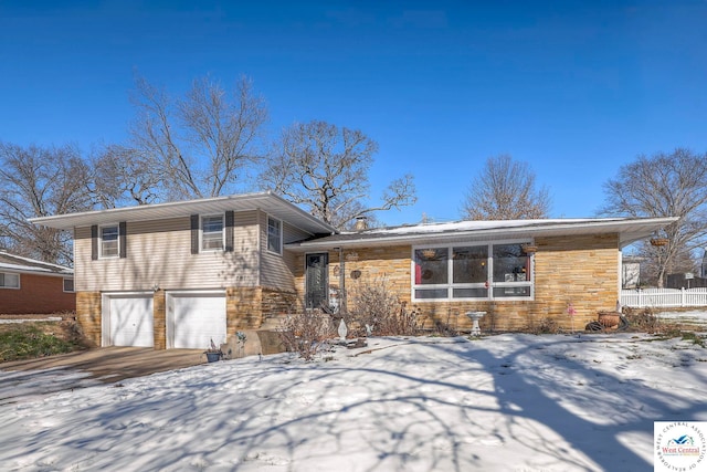 split level home featuring a garage, stone siding, and concrete driveway