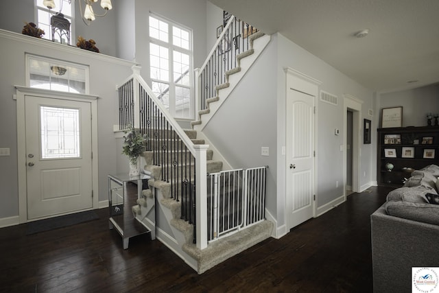 entrance foyer featuring visible vents, baseboards, stairs, hardwood / wood-style floors, and a high ceiling