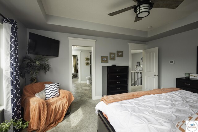 carpeted bedroom featuring a tray ceiling, a ceiling fan, and baseboards