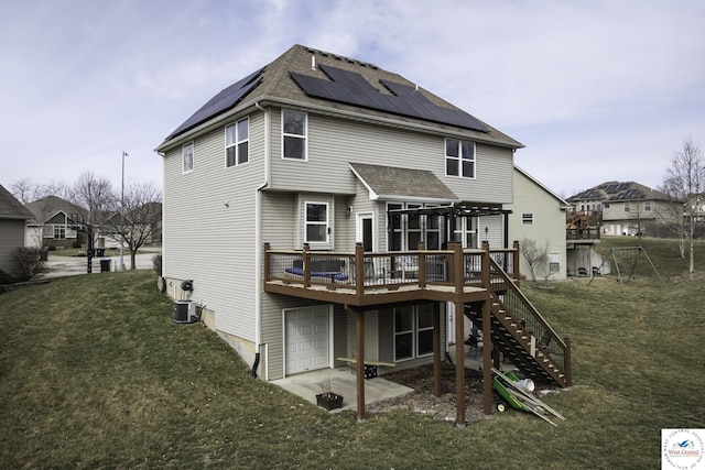 back of house featuring solar panels, a yard, stairs, a garage, and a deck