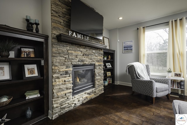 living area featuring recessed lighting, baseboards, dark wood-type flooring, and a fireplace