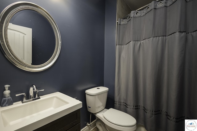 bathroom featuring toilet, vanity, and a shower with curtain