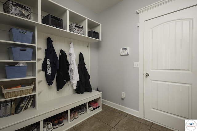 mudroom with baseboards and dark tile patterned flooring