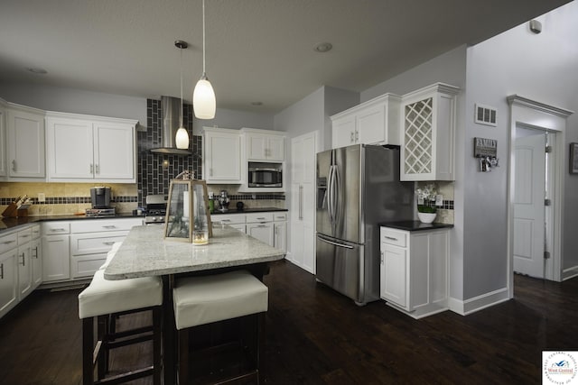 kitchen featuring stainless steel appliances, visible vents, white cabinets, and wall chimney range hood