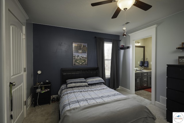 carpeted bedroom with a sink, visible vents, baseboards, and ensuite bath