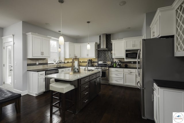 kitchen with a sink, stainless steel appliances, wall chimney exhaust hood, and white cabinets